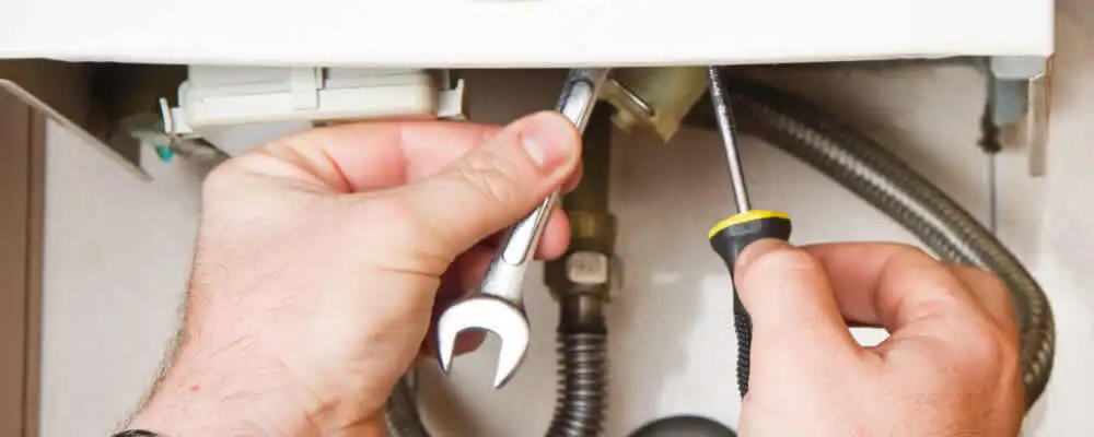 Boiler repair technician tightening pipe fittings and connections in Kansas City, KS