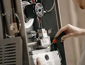 Furnace repair technician inspecting internal components and wiring in Kansas City, KS