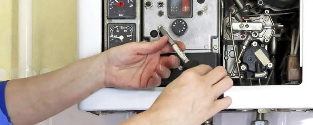 Heating repair technician adjusting boiler controls and components in Kansas City, KS