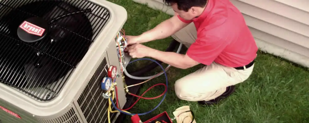 HVAC technician servicing an outdoor air conditioner unit in Kansas City, KS