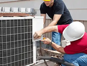 HVAC technicians repairing an outdoor AC unit on a rooftop in Kansas City, KS