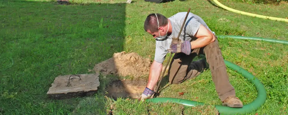 Septic pumping technician servicing a residential septic tank in Kansas City, KS