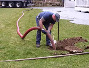 Septic pumping technician servicing a residential septic tank with a vacuum hose in Kansas City, KS