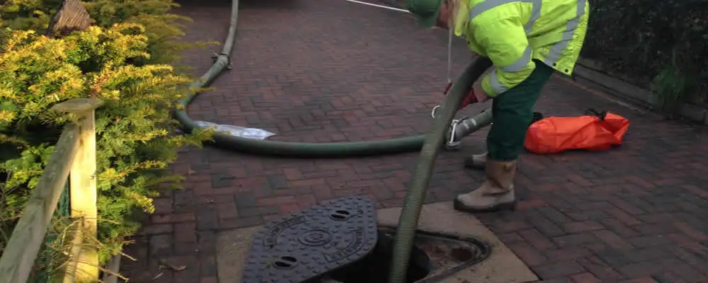 Septic tank cleaning technician servicing a septic tank with a vacuum hose in Kansas City, KS