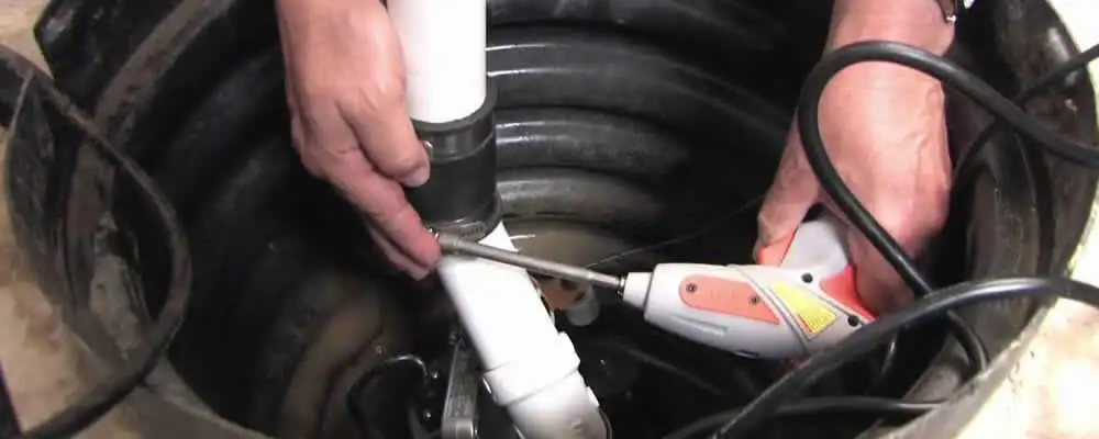 Sump pump installation technician connecting PVC discharge piping in Kansas City, KS